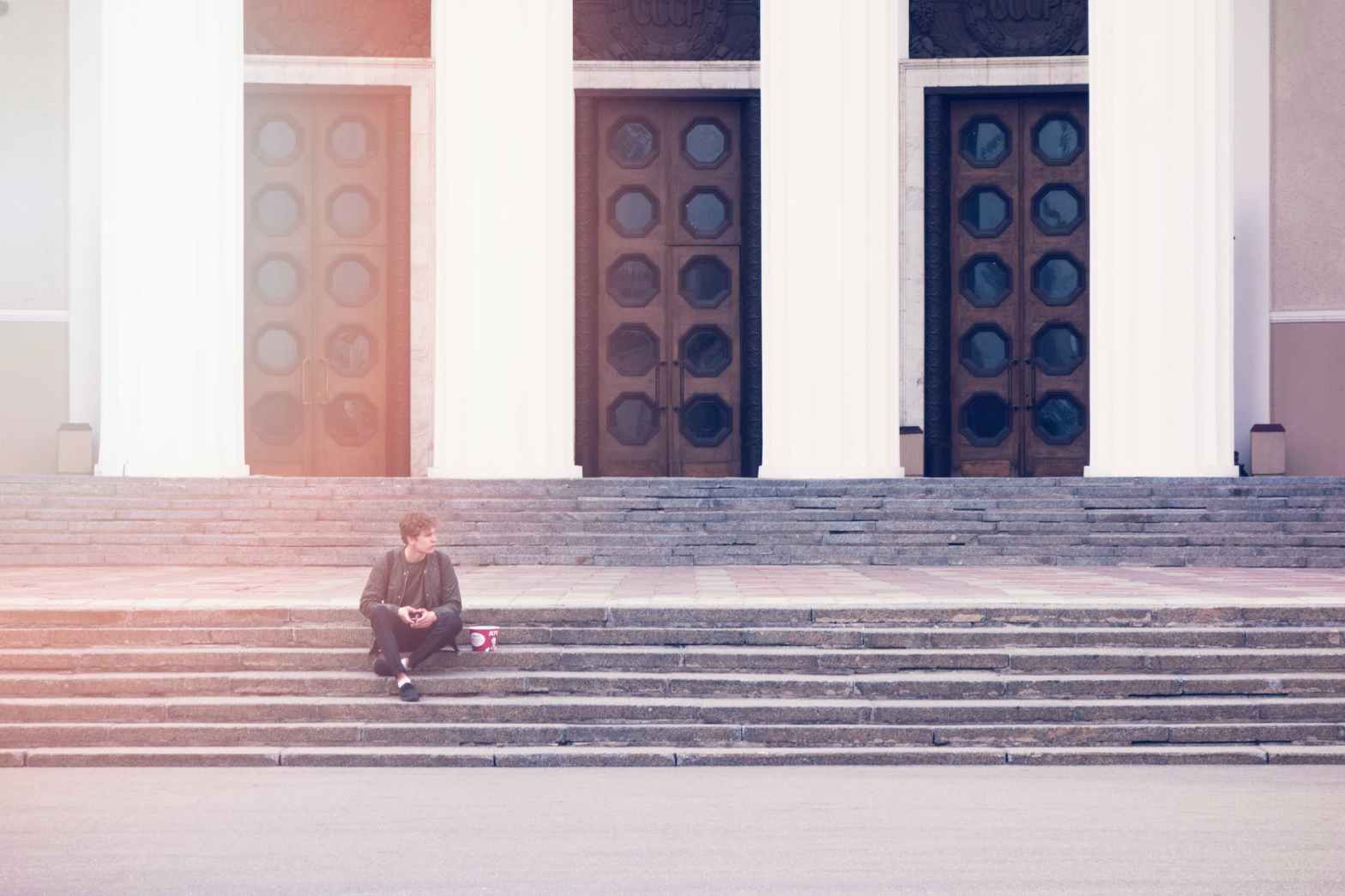 man sitting on a concrete stair waiting for someone during daytime